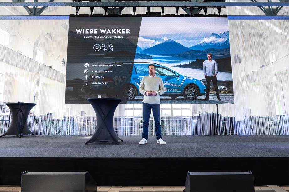 Speaker Wiebe Wakker on a stage in front of a big screen